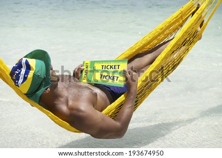 Brazilian man relaxing in beach hammock with two Brazil tickets