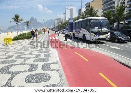RIO DE JANEIRO, BRAZIL - APRIL 1, 2014: A city bus stops beside the boardwalk bike path on Avenida Vieira Souto in Ipanema, recently painted red for safety.