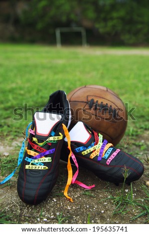 Good luck soccer football boots soccer cleats laced with Brazilian wish ribbons on rustic dirt grass pitch with vintage brown football