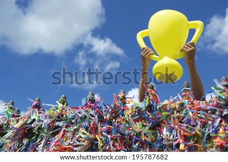 Hands holding good luck championship trophy at wall of Brazilian wish ribbons at the Bonfim church in Salvador Bahia Brazil