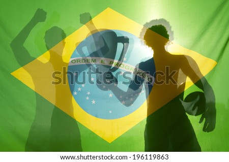 Shadow silhouettes of football players celebrating holding winning trophy and football against Brazilian flag in bright sunlight