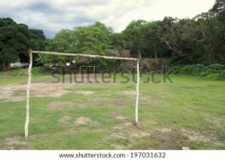 Simple tropical Brazilian football pitch with rustic goal posts surrounded by trees