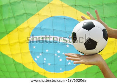 Football goalie making a save catching soccer ball in front of goal net Brazilian flag background