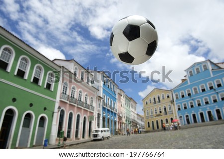 Football soccer ball flying above colorful colonial architecture in cobblestone plaza at historic city center of Pelourinho Salvador da Bahia Brazil
