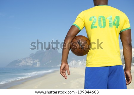 Footballer in team Brazil kit 2014 shirt holding vintage soccer ball Ipanema Beach Rio de Janeiro