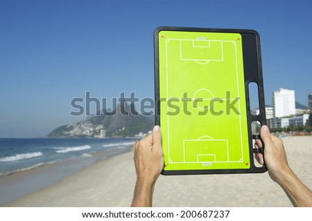 Hands holding football tactics board on empty beach at Ipanema Rio de Janeiro Brazil