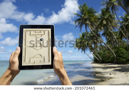 Hands holding digital tablet football tactics board on the beach in Nordeste Bahia Brazil