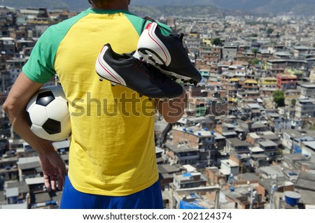 Brazilian football player standing in Brazil colors kit holding soccer ball in front of favela slum background in Rio de Janeiro