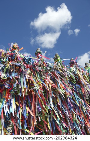 Colorful religious Brazilian wish ribbons tied on gate at the Church of Nosso Senhor do Bonfim in Salvador Brazil under bright blue sky