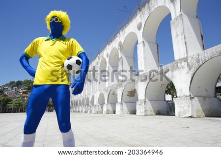 Blue Brazilian football player in yellow shirt holding soccer ball standing at Lapa Arches Rio de Janeiro Brazil
