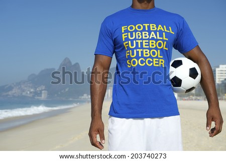 Brazilian football player in multi language message t-shirt holding soccer ball Ipanema Beach Rio de Janeiro Brazil