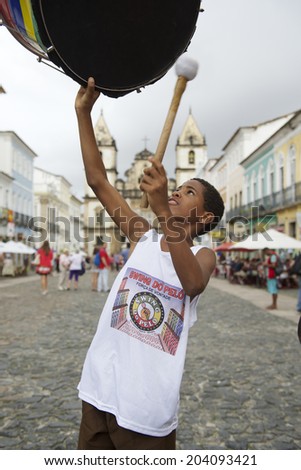 SALVADOR, BRAZIL - OCTOBER 15, 2013: Young member of Brazilian drumming group shows off his skills on a plaza in the historical center of Pelourinho, famous for its percussion bands.