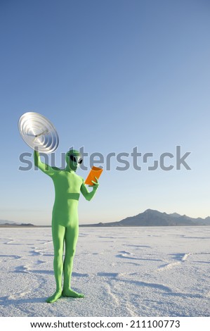 Green alien holding orange tablet with satellite dish communication system