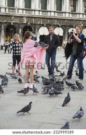 VENICE, ITALY - APRIL 17, 2013: Tourists pose for photographs with the pigeons in Saint Mark\'s Square.