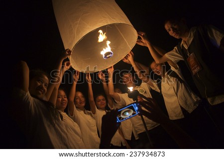 CHIANG MAI, THAILAND - OCTOBER 25, 2014: Group of young Thai people launch a sky lantern on the night of the annual festival known as Yee Peng (Yi Peng).
