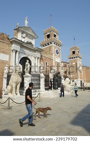 VENICE, ITALY - CIRCA APRIL, 2013: Italian man walks his dog in front of the traditional architecture of the Porta Magna gate in the Venetian Arsenal neighborhood.