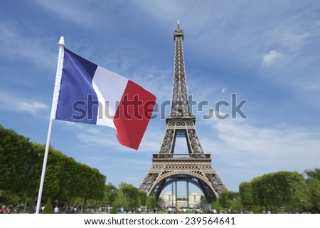 Eiffel Tower with French flag flying in bright summer sky