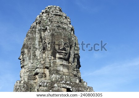 Angkor Wat Temple of Bayon stone face sculpture ruins in a tower against blue sky