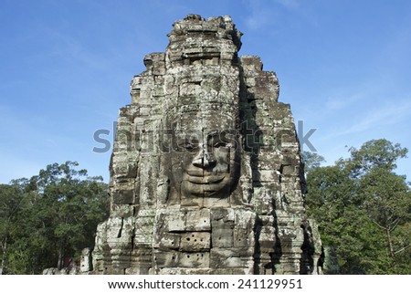 Angkor Thom Temple of Bayon stone face sculpture green trees blue sky
