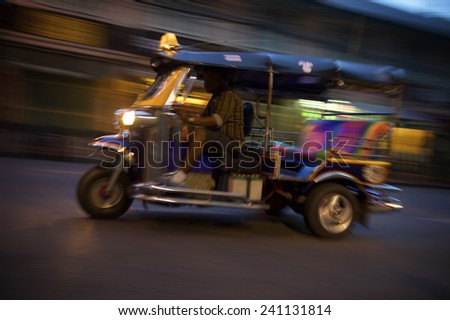 Bangkok Thailand tuk-tuk taxi zooms by in a night blur