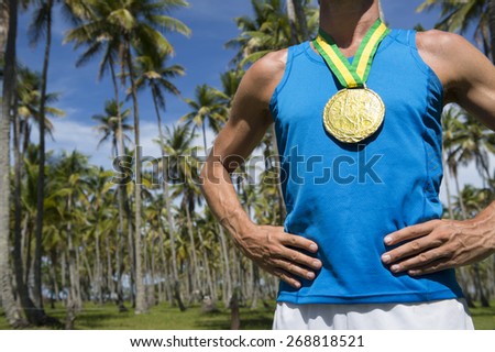 Rio 2016 first place athlete wearing gold medal standing outdoors with hands on hips in grove of tropical palm trees in Brazil