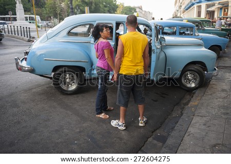 HAVANA, CUBA - JUNE, 2011: Cuban passengers wait to enter a classic American taxi on the Prado in Central Havana.