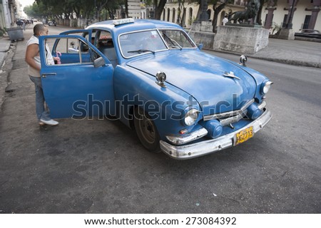 HAVANA, CUBA - JUNE, 2011: Cuban passengers enter a classic American taxi on a street in Central Havana.