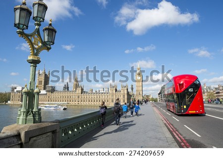 LONDON, UK - APRIL 27, 2015: Modern double-decker bus passes pedestrians walking in front of Big Ben and Houses of Parliament on Westminster Bridge.