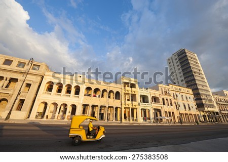 Moto rickshaw drives in front of colonial architecture lining the Malecon seafront road in central Havana, Cuba