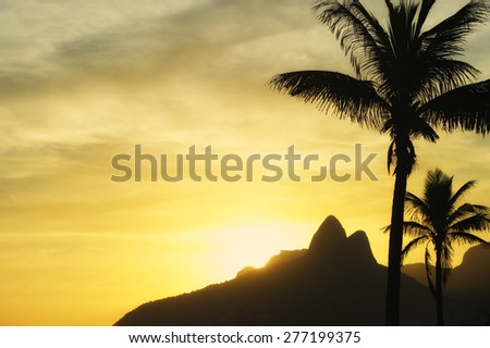 Sunset in Rio de Janeiro Ipanema Beach Brazil with Two Brothers Dois Irmaos Mountain and palm trees silhouettes