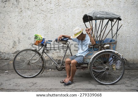 CHIANG MAI, THAILAND - NOVEMBER 07, 2014: Driver of a traditional bicycle rickshaw takes a nap on a quiet side street.