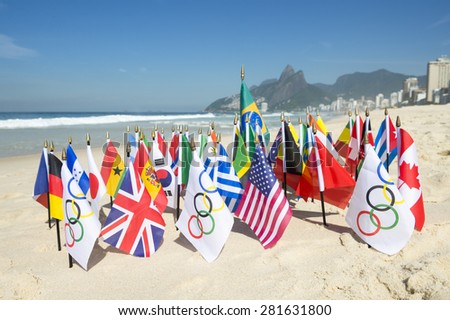 RIO DE JANEIRO, BRAZIL - MARCH 20, 2015: Olympic flags fly together with an array of Brazil and international flags on the sand against a skyline view of Ipanema Beach.