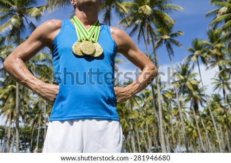 First place athlete wearing gold medals standing outdoors with hands on hips in grove of tropical palm trees in Brazil