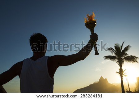 Silhouette of athlete standing with sport torch at the Rio de Janeiro Brazil sunset skyline at Ipanema Beach