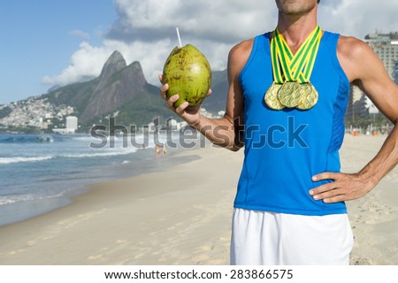 Champion athlete wearing gold medals celebrating with coconut on Ipanema Beach Rio de Janeiro Brazil