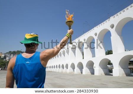 Young athletic man standing with sport torch in front of the Arcos da Lapa Arches in Rio de Janeiro Brazil