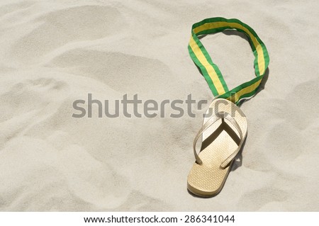First place flip flop gold medal shining in the sand with a Brazilian colors ribbon in Rio de Janeiro Brazil
