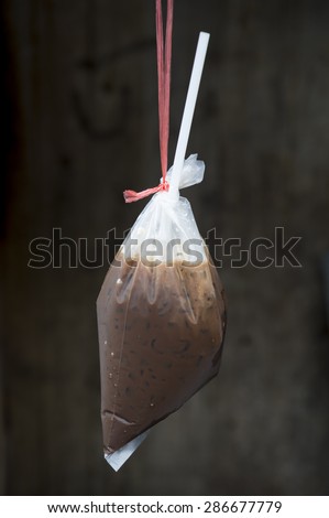 Fresh traditional Thai style iced coffee with condensed milk served in a handy plastic bag with a straw