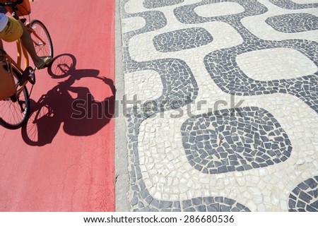 Abstract Ipanema Beach Rio de Janeiro boardwalk pattern with cyclist shadow on stretch of red bike path