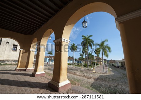 View of the Plaza Mayor between archways in the portico of the historic colonial architecture of the Palacio Brunet in the UNESCO heritage center of Trinidad, Cuba