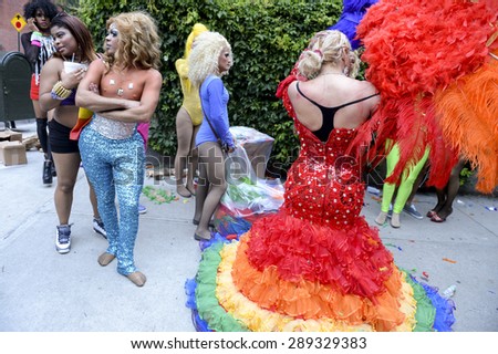 NEW YORK CITY, USA - JUNE 30, 2013: Drag queen in dramatic rainbow dress celebrates the annual gay pride event with her friends.