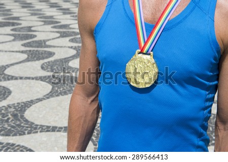 Gold medal first place athlete standing with gay pride rainbow ribbon at the Copacabana Beach sidewalk in Rio de Janeiro Brazil