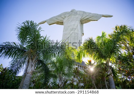 RIO DE JANEIRO, BRAZIL - MARCH 05, 2015: Morning sun shines through palm trees at the base of the Christ the Redeemer monument at Corcovado Mountain.