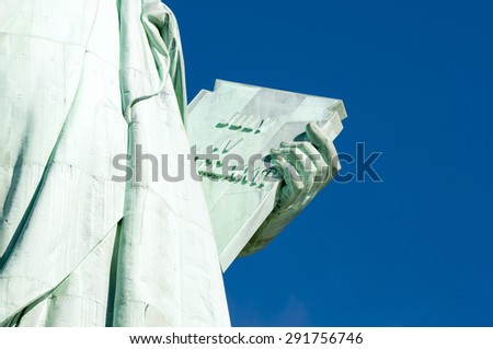 July 4 Independence Day tablet held by the Statue of Liberty close-up against bright blue sky