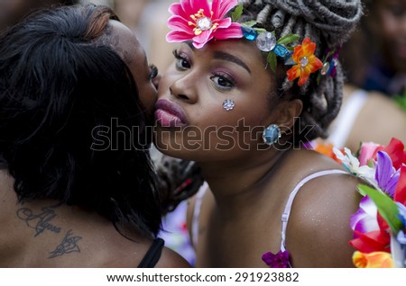 NEW YORK CITY, USA - JUNE 28, 2015: Young woman decorated with colorful flowers kisses her friend in greeting at the annual Pride Parade in Greenwich Village.