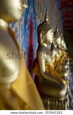 Row of golden seated buddhas close up in a Buddhist temple in Bangkok Thailand