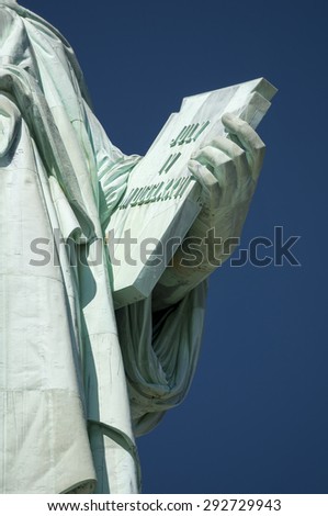 July 4, 1776 Independence Day tablet held by the Statue of Liberty close-up against bright blue sky