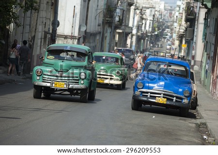 HAVANA, CUBA - JUNE, 2011: Vintage American taxi cars share the road on a long street in Central Havana.