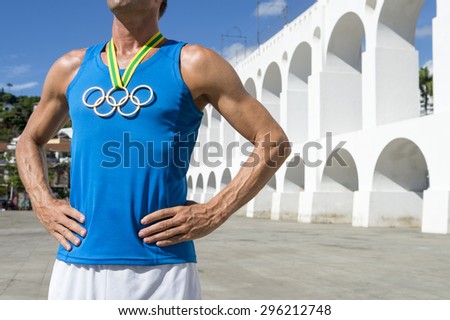 RIO DE JANEIRO, BRAZIL - MARCH 6, 2015: Athlete wearing Olympic rings gold medal stands outdoors in the plaza in front of the famous Lapa Arches landmark.