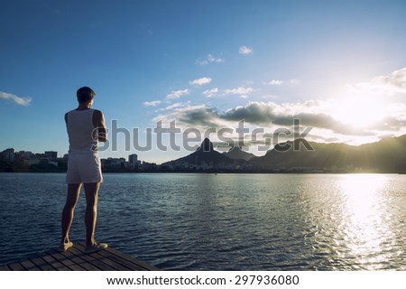 Man standing with arms crossed at sunset in front of Rio de Janeiro Brazil skyline at Lagoa lagoon